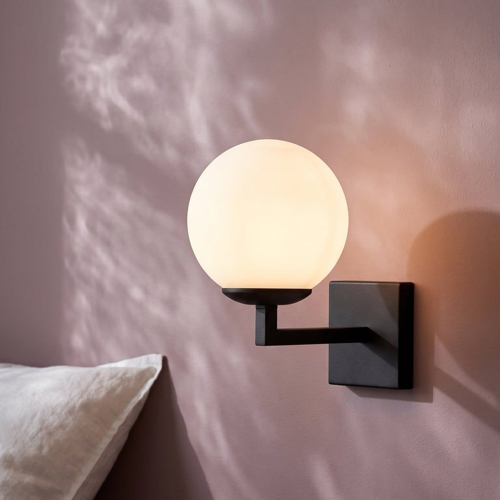 Applique murale globe noir allumée dans une chambre avec tête de lit