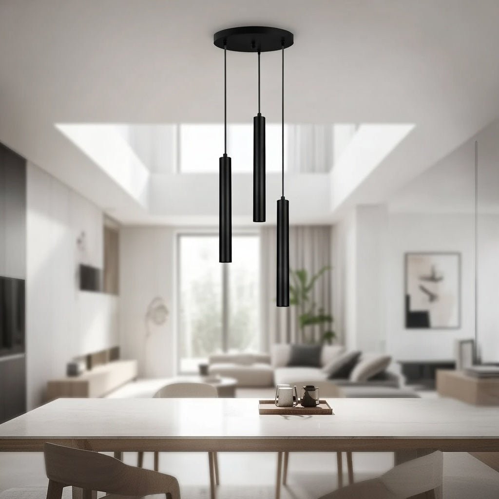 Lustre triple tubes noir installé au-dessus d'une table à manger.