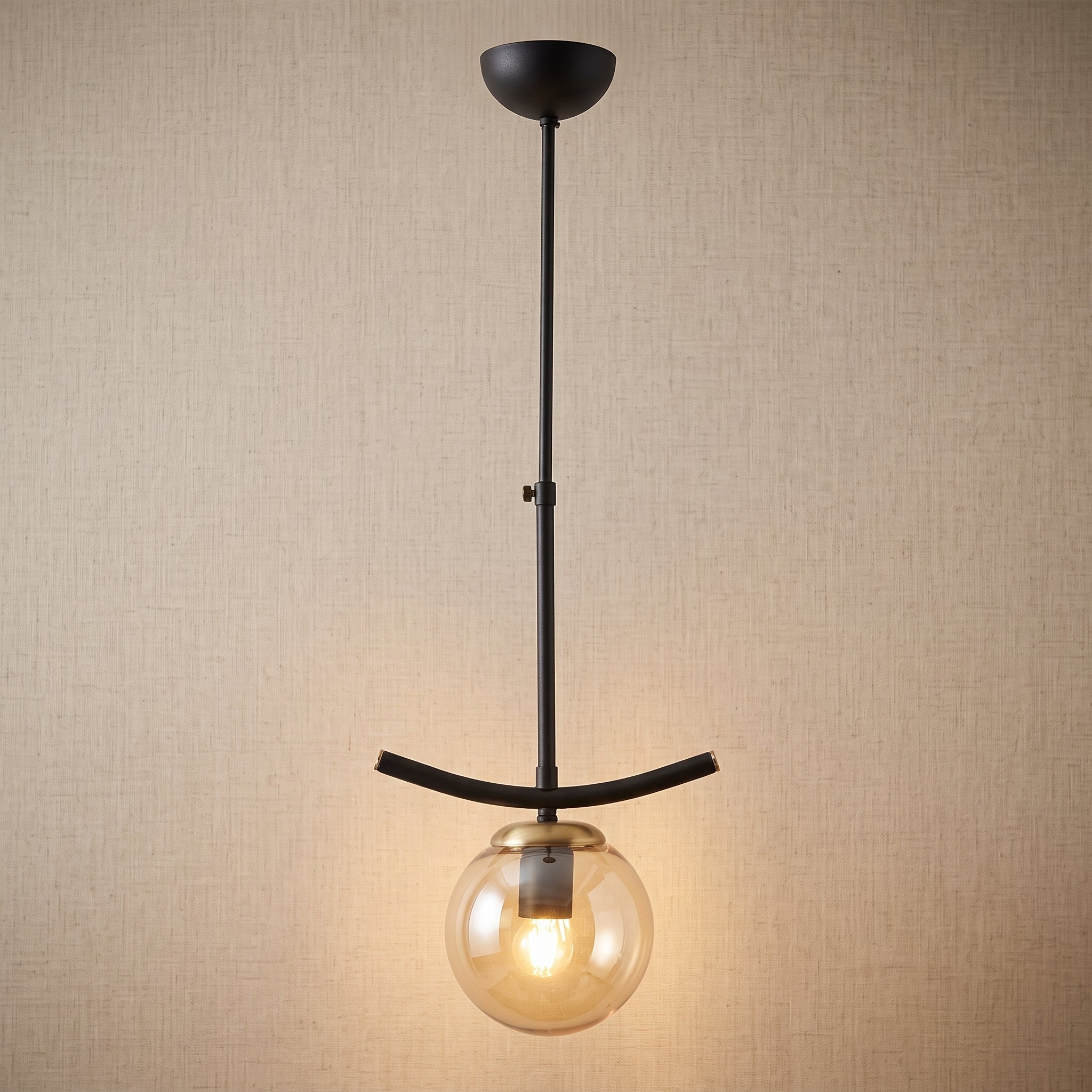 Suspension globe ambré structure noire détails dorés design moderne