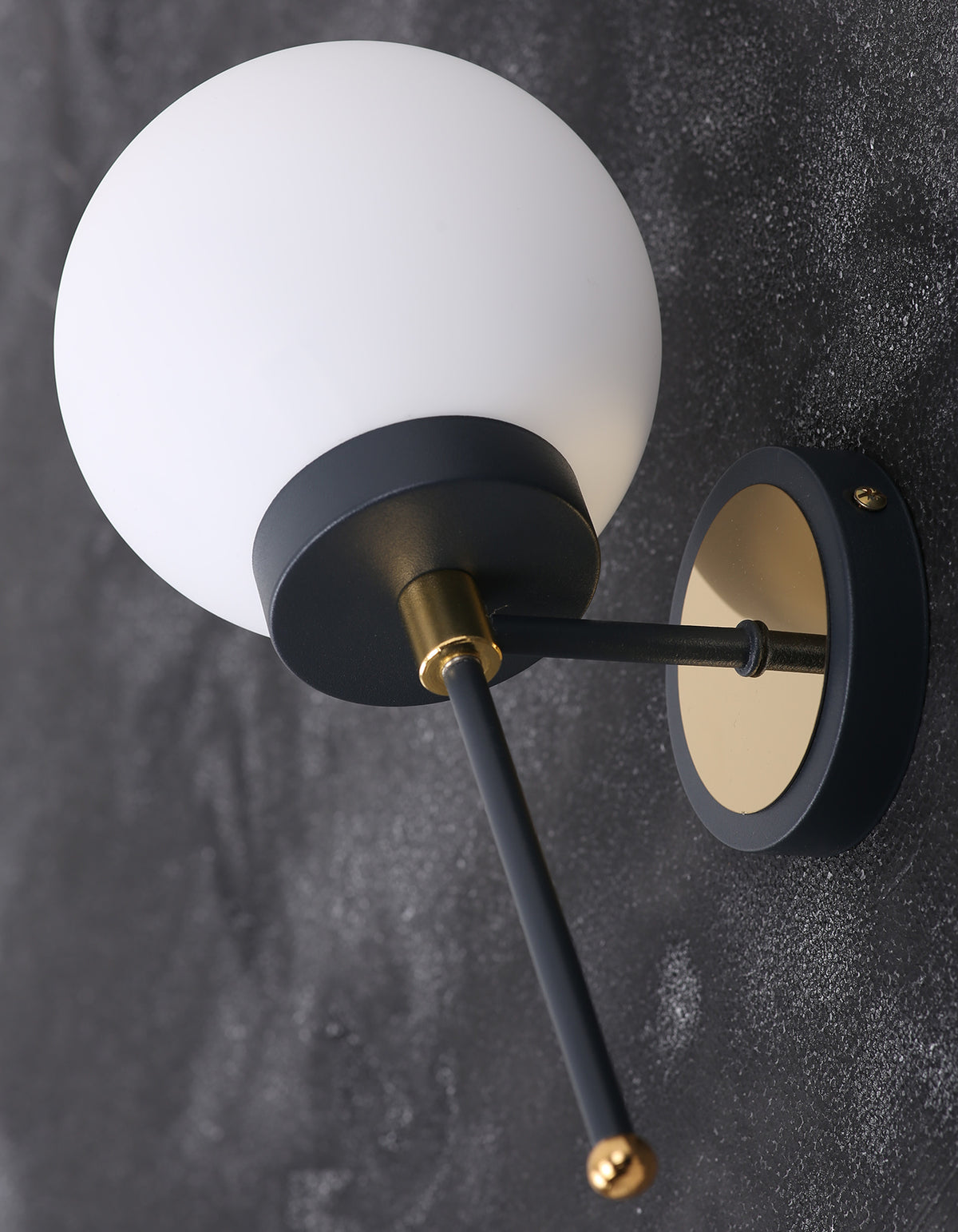 Détail de l'applique murale globe blanc opale avec rosace dorée, structure noire et finition dorée