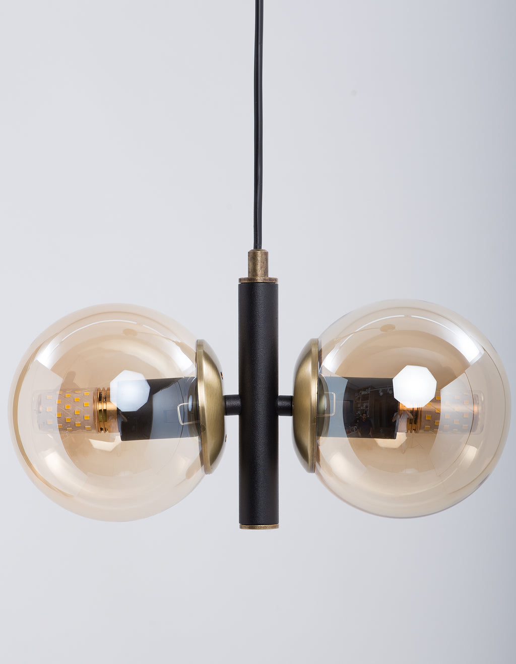 Détail des deux globes en verre ambré et de la structure noire avec finition dorée
