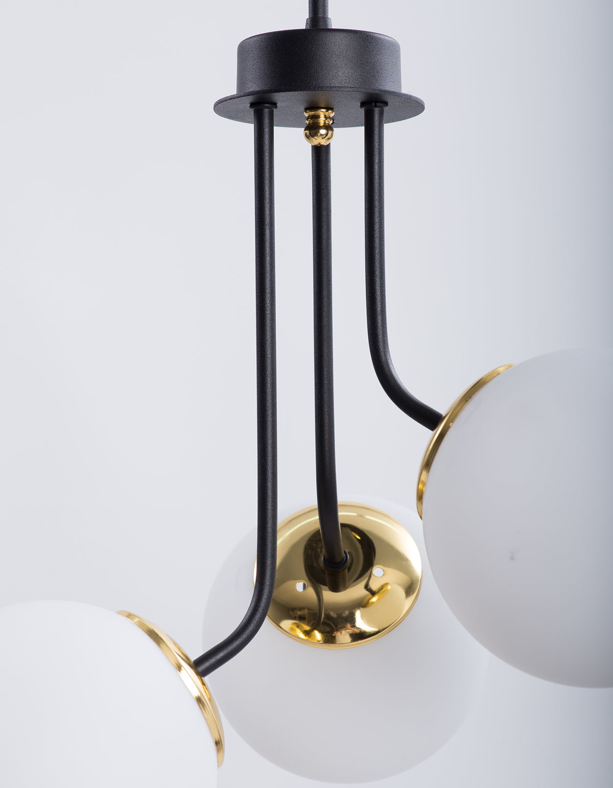 Détail d’un globe en verre blanc opale et de la structure noir mat avec détails dorés