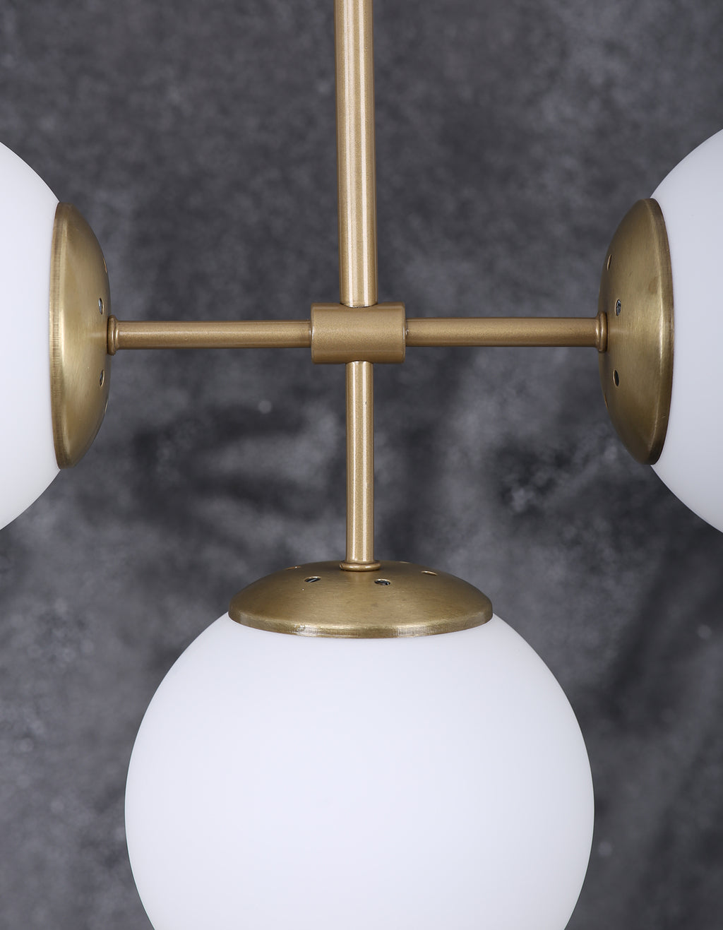 Détail d’un globe en verre blanc opalin et de la structure en laiton brossé
