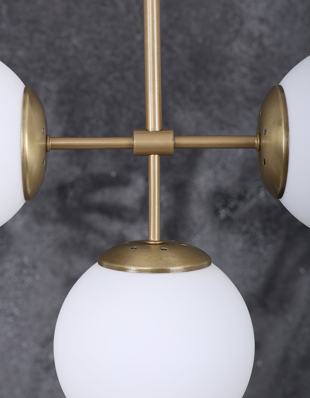 Détail d’un globe en verre blanc opalin et de la structure en laiton brossé
