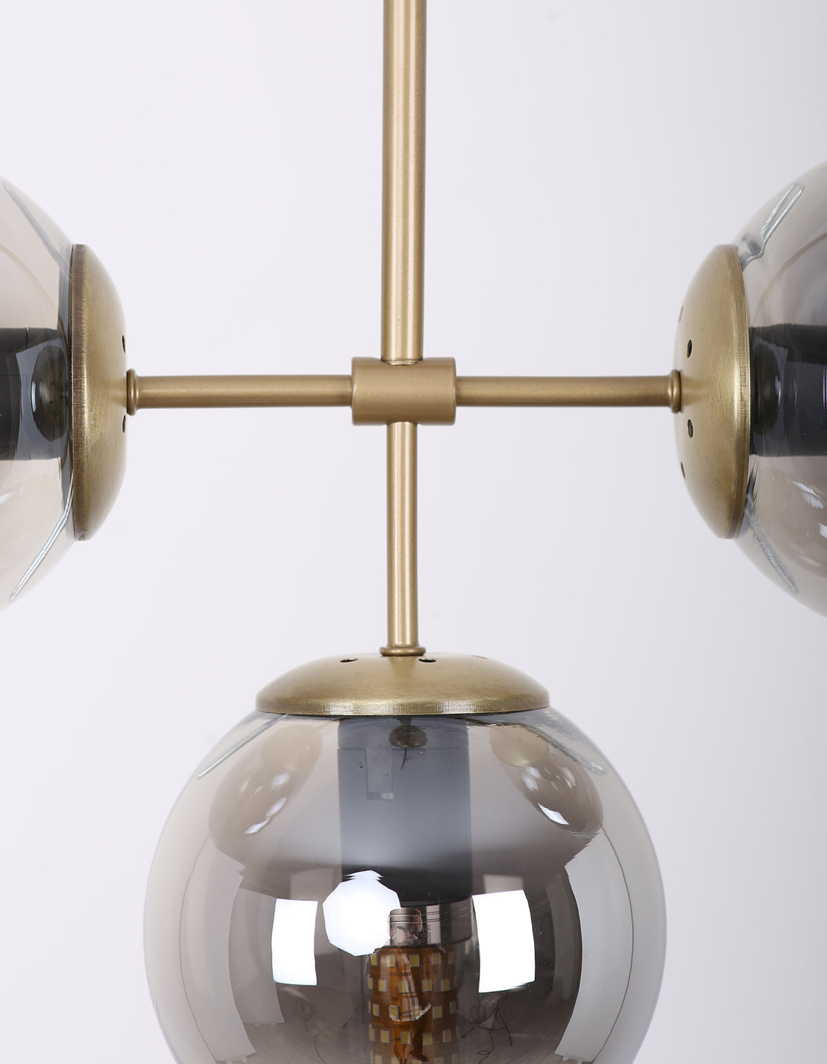 Détail d’un globe en verre fumé et de la structure en laiton brossé de la suspension