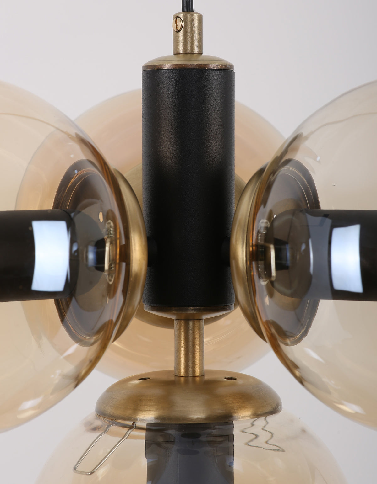 Détail de la structure noir mat et des détails laiton entre les globes en verre ambré