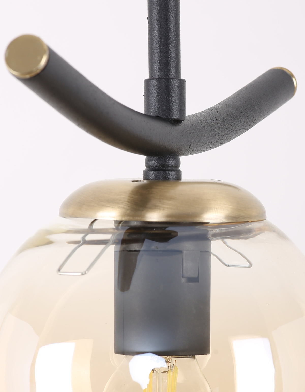 Détail de la structure noire et des finitions dorées de la suspension globe ambré