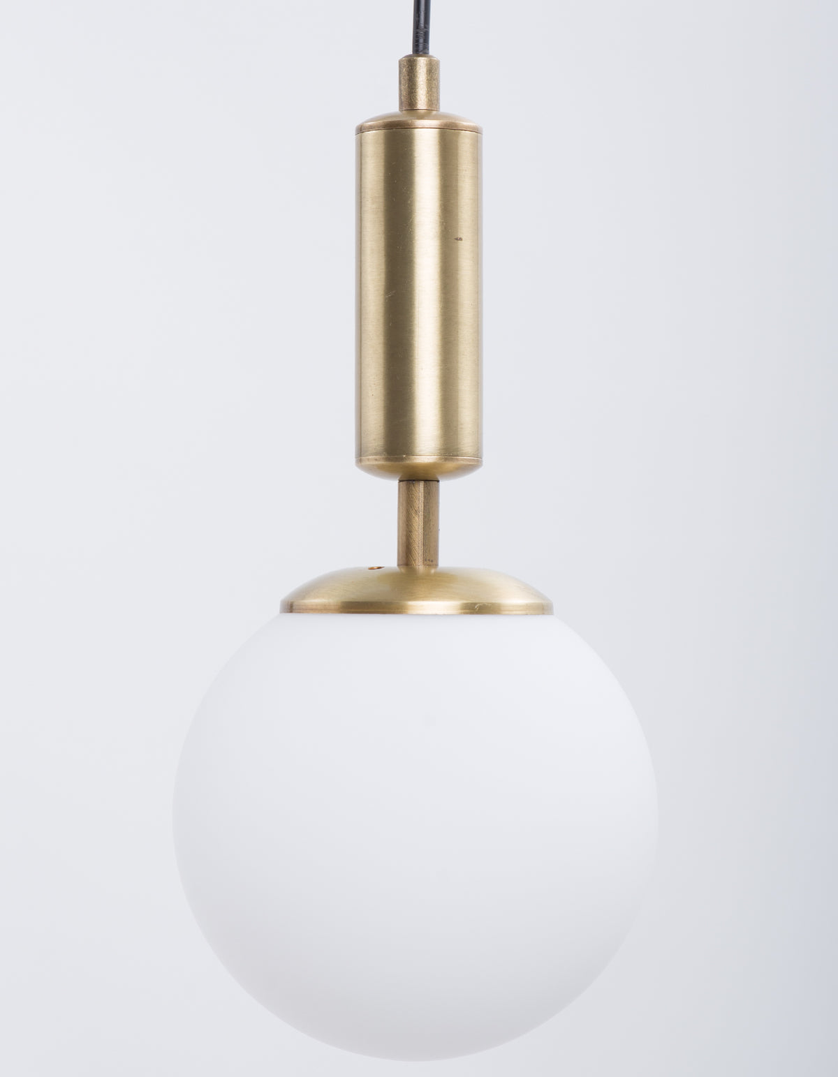 Détail du globe en verre blanc opale et du cylindre finition laiton brossé de la suspension