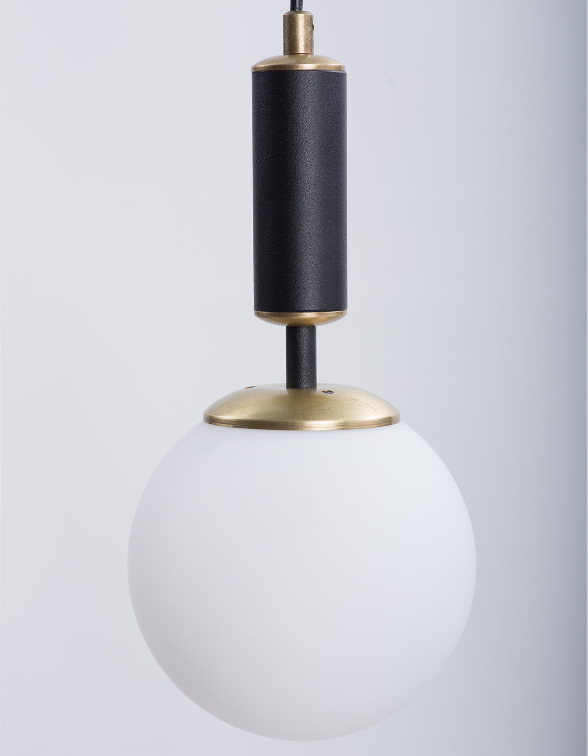 Détail du globe en verre blanc opale et de la finition laiton de la suspension