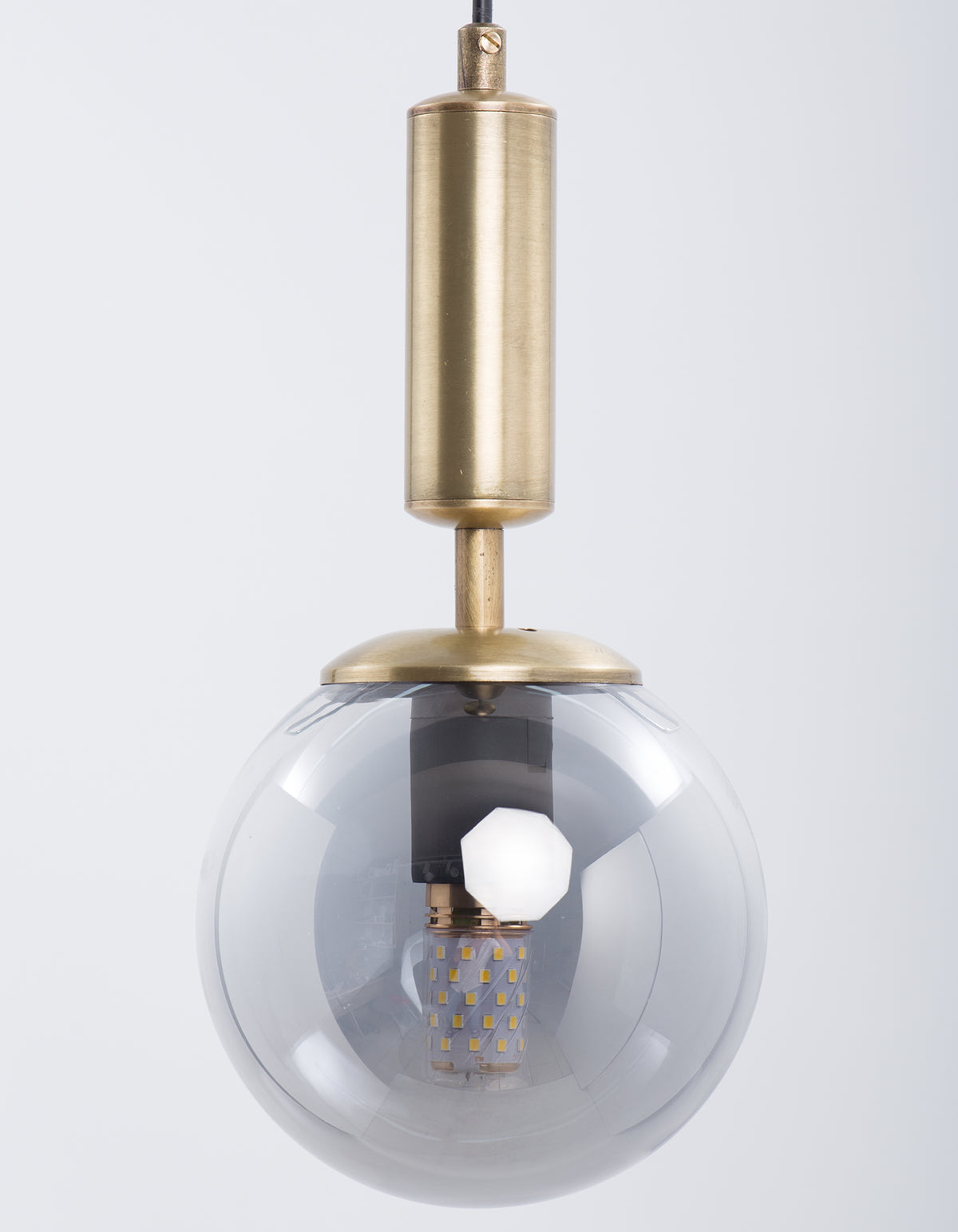 Détail du globe en verre fumé transparent et du cylindre finition laiton brossé de la suspension