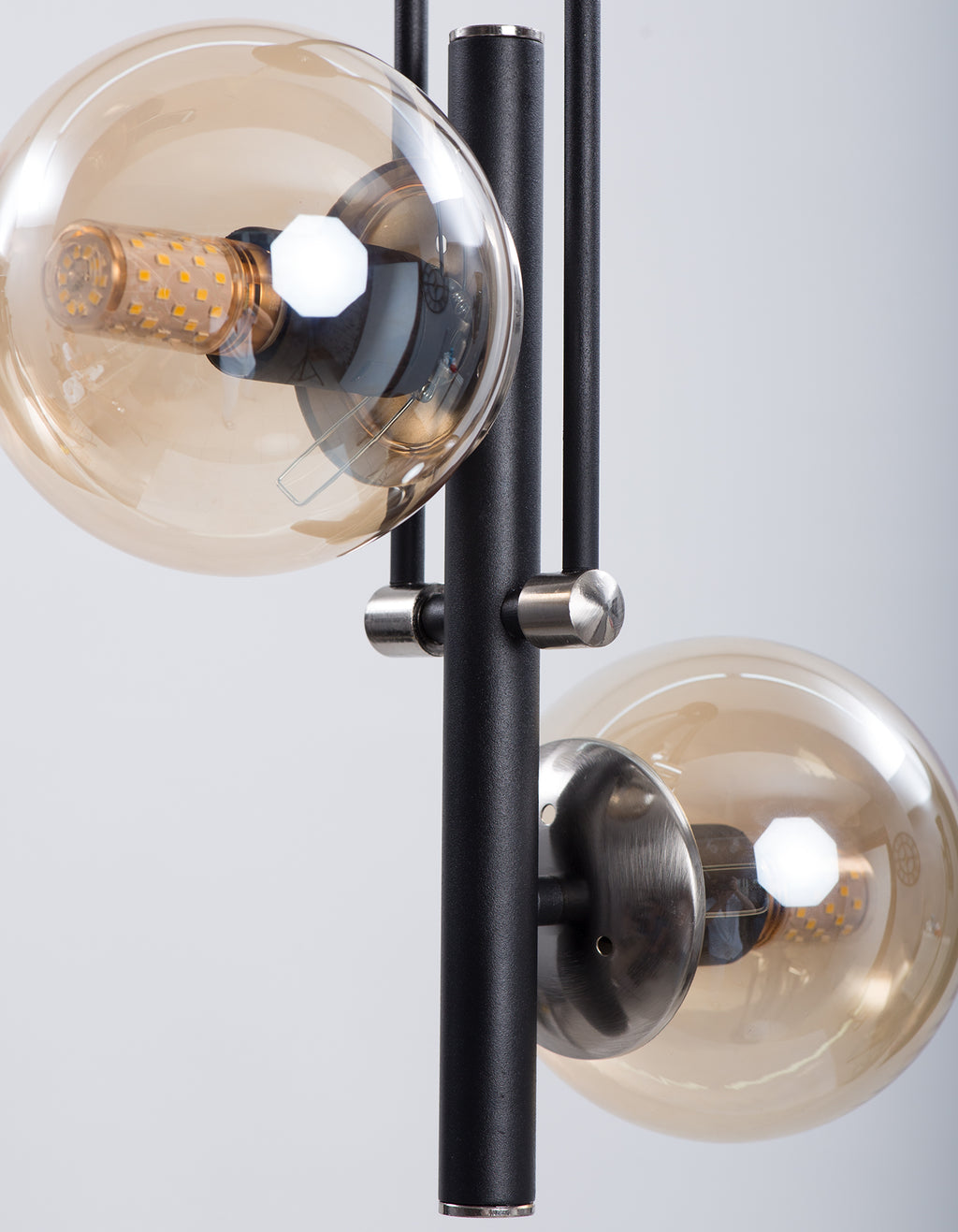 Détail des globes en verre ambré et des fixations chromées sur structure noire
