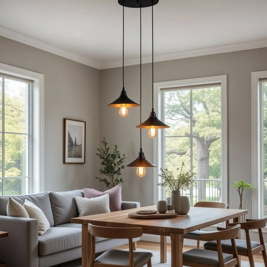Lustre 3 lumières noir et doré installé au-dessus d’une table à manger en bois