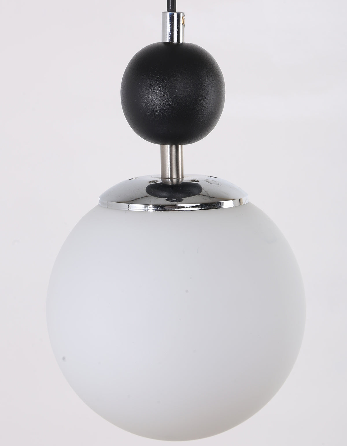 Gros plan sur le globe blanc opale, la sphère noire et la fixation chromée du lustre suspendu