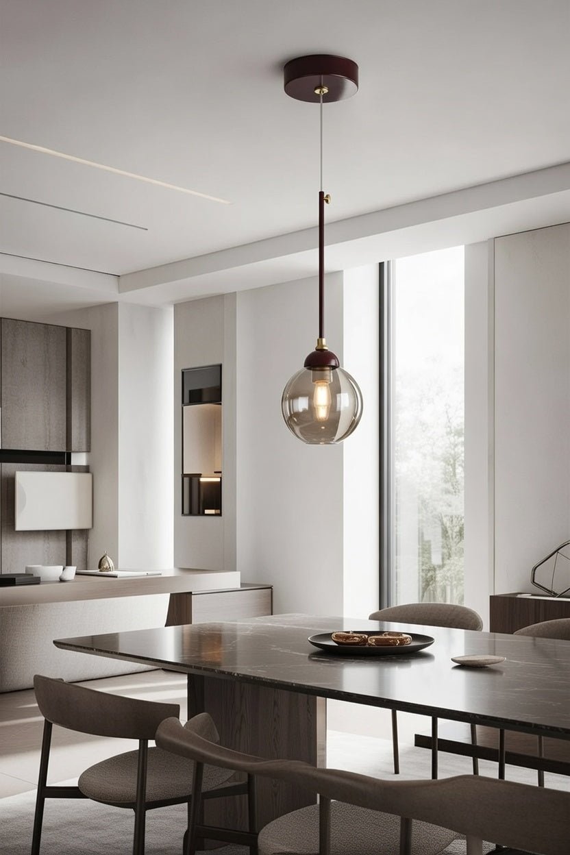 Suspension globe fumé marron installée au-dessus d’une table à manger contemporaine
