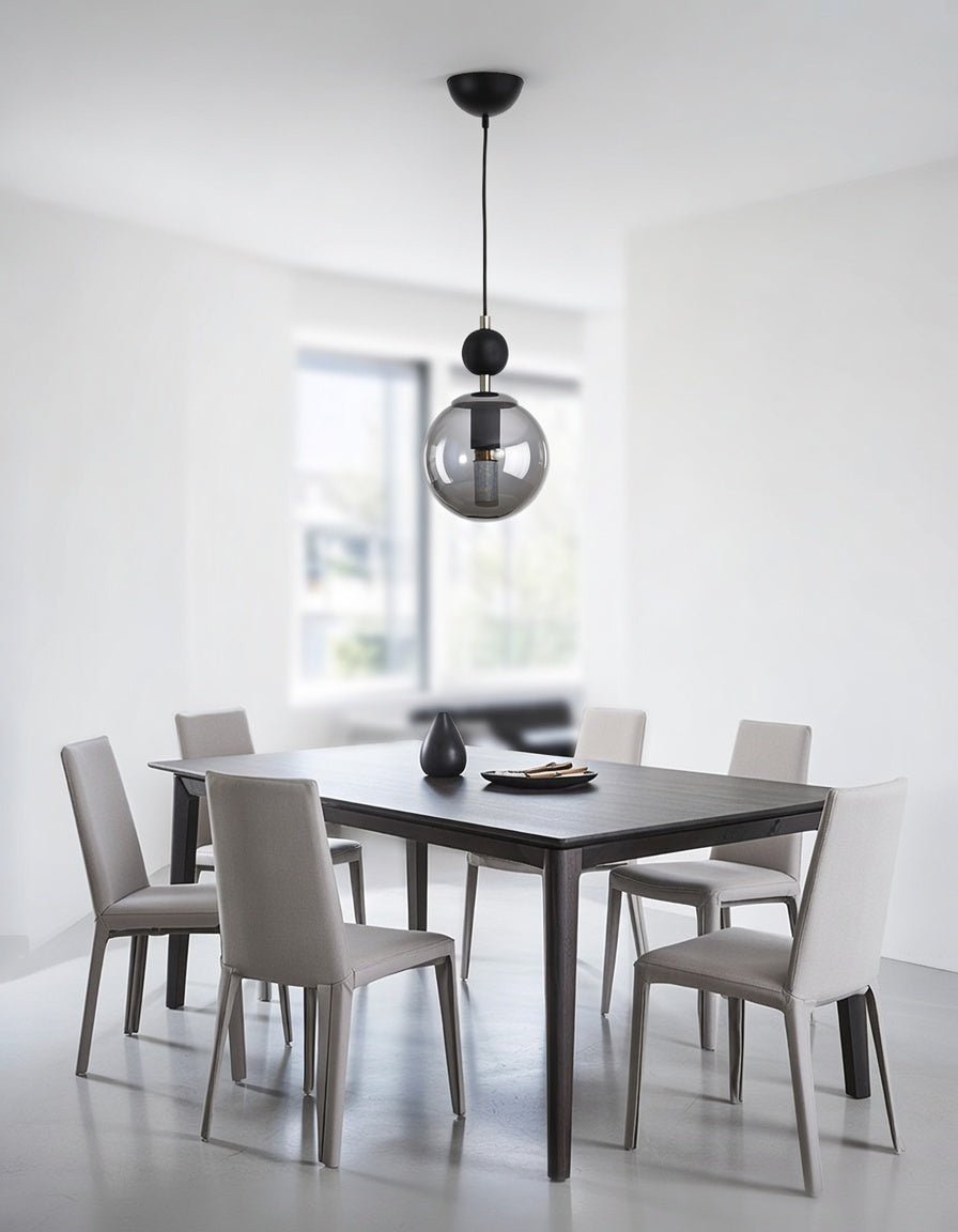 Lustre suspendu globe transparent fumé installé au-dessus d’une table à manger contemporaine