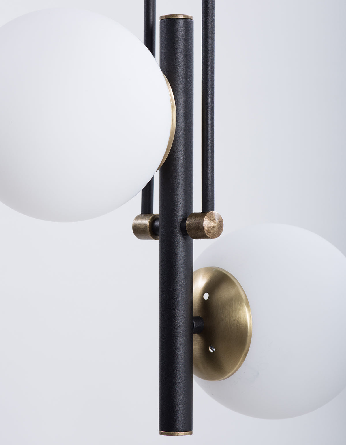 Détail des globes en verre opale blanc et des finitions dorées sur structure noire