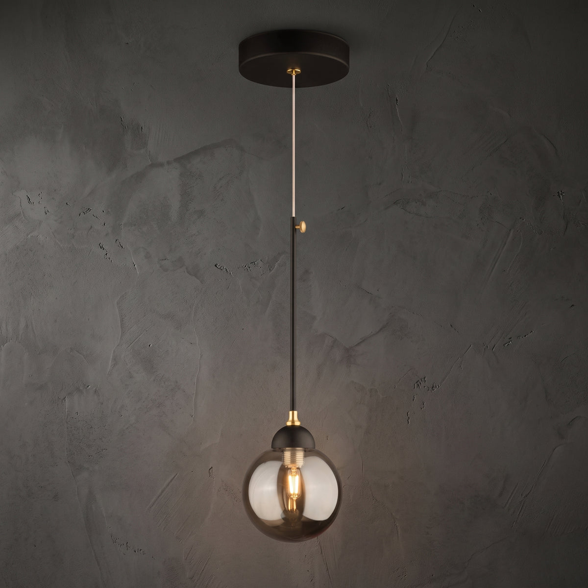 Lustre suspendu globe en verre fumé avec structure noire et détails dorés, allumé