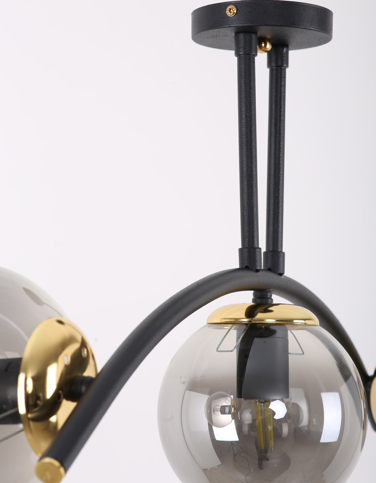 Détail de la structure noir mat, des finitions dorées et d’un globe en verre fumé
