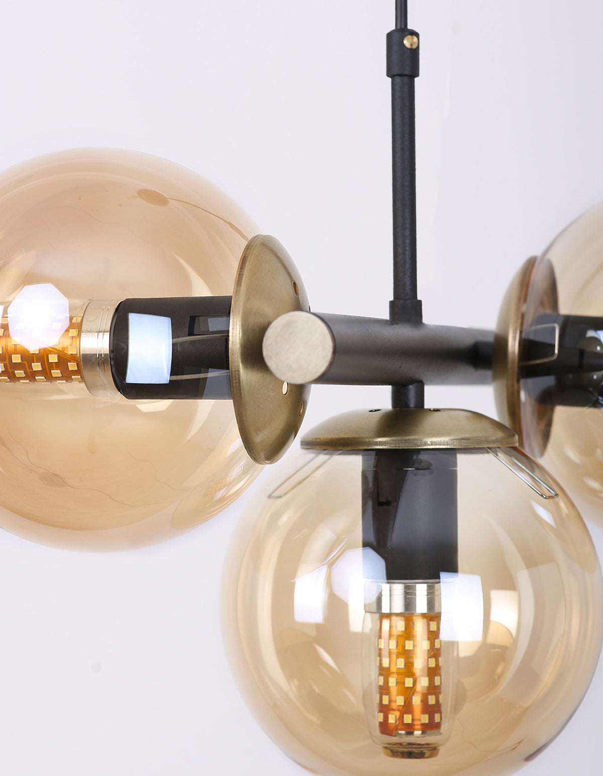 Détail des globes en verre ambré et de la structure noire avec finitions dorées
