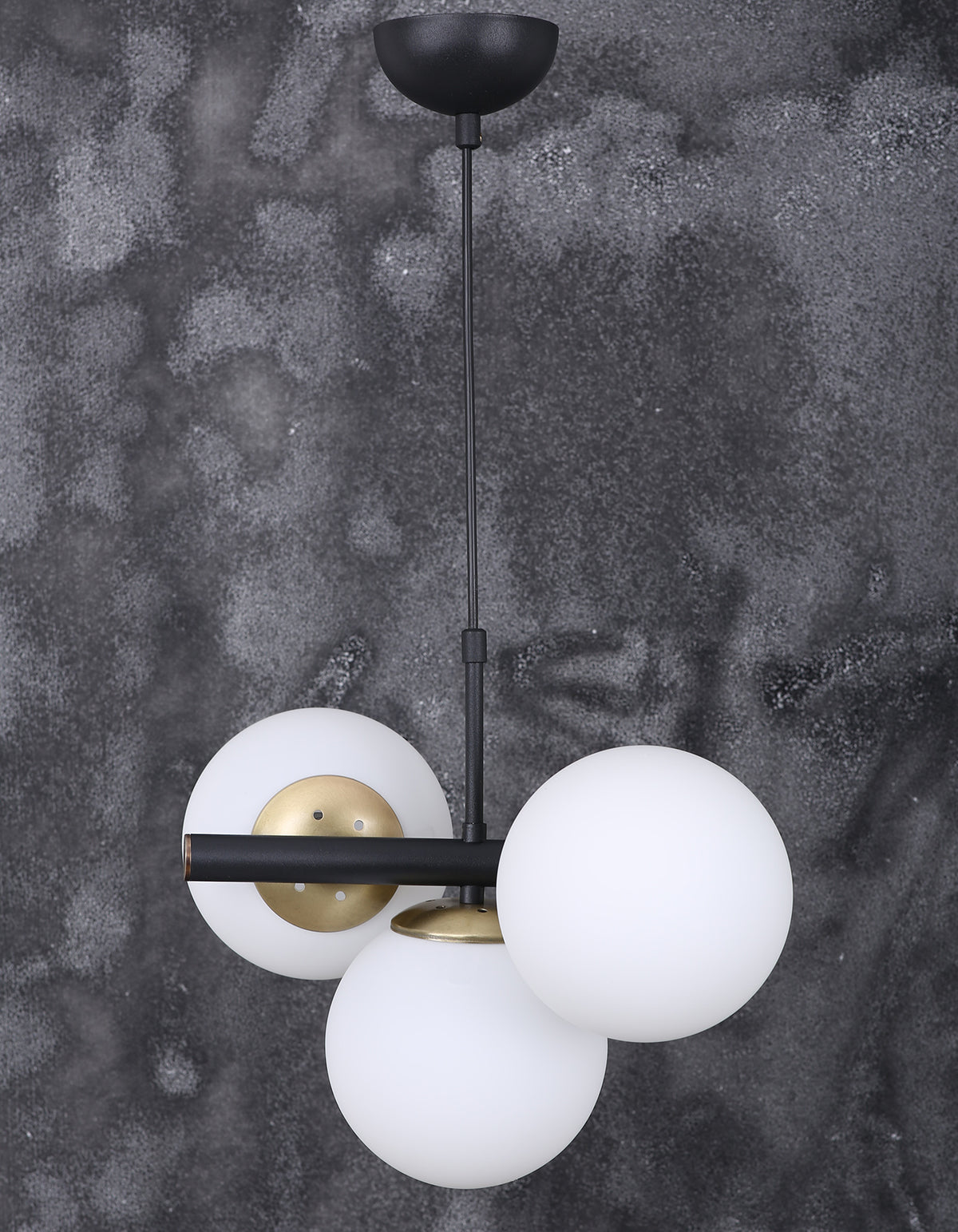 Détail des globes en verre blanc opalin et des finitions dorées de la suspension