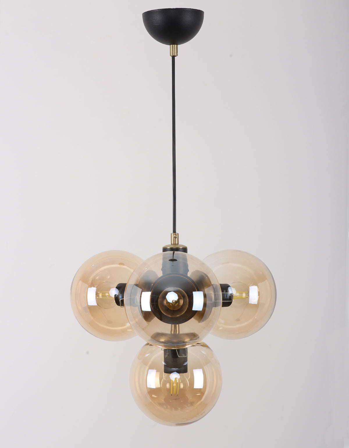 Suspension 4 globes en verre ambré allumée avec structure noir mat et détails laiton