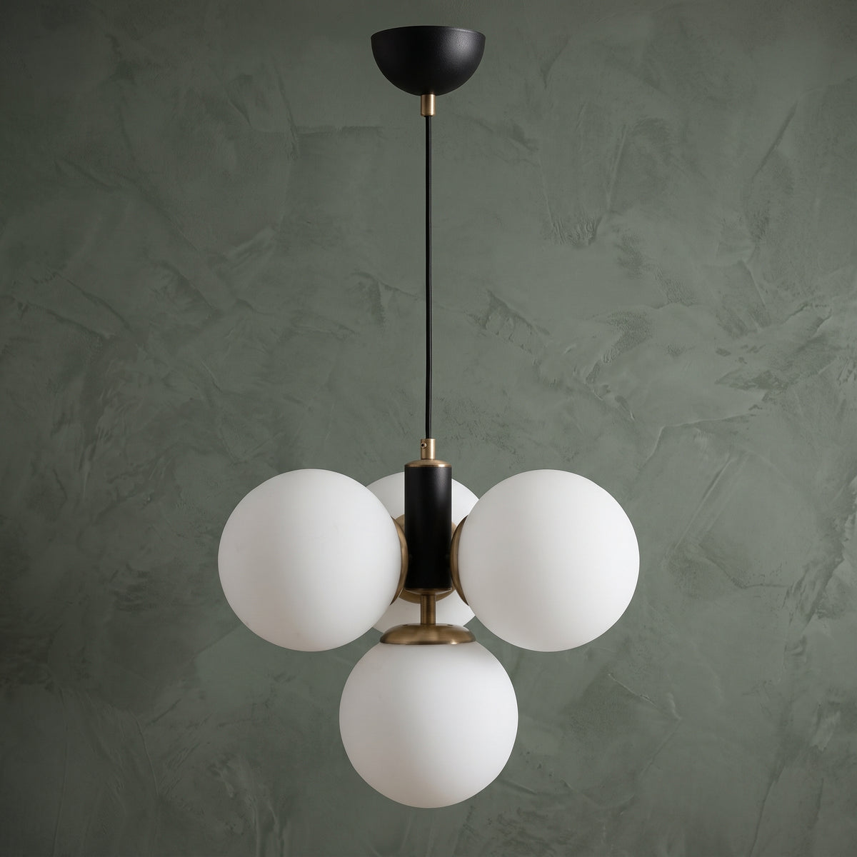 Suspension 4 globes en verre blanc opale avec structure noir mat et détails laiton sur fond texturé