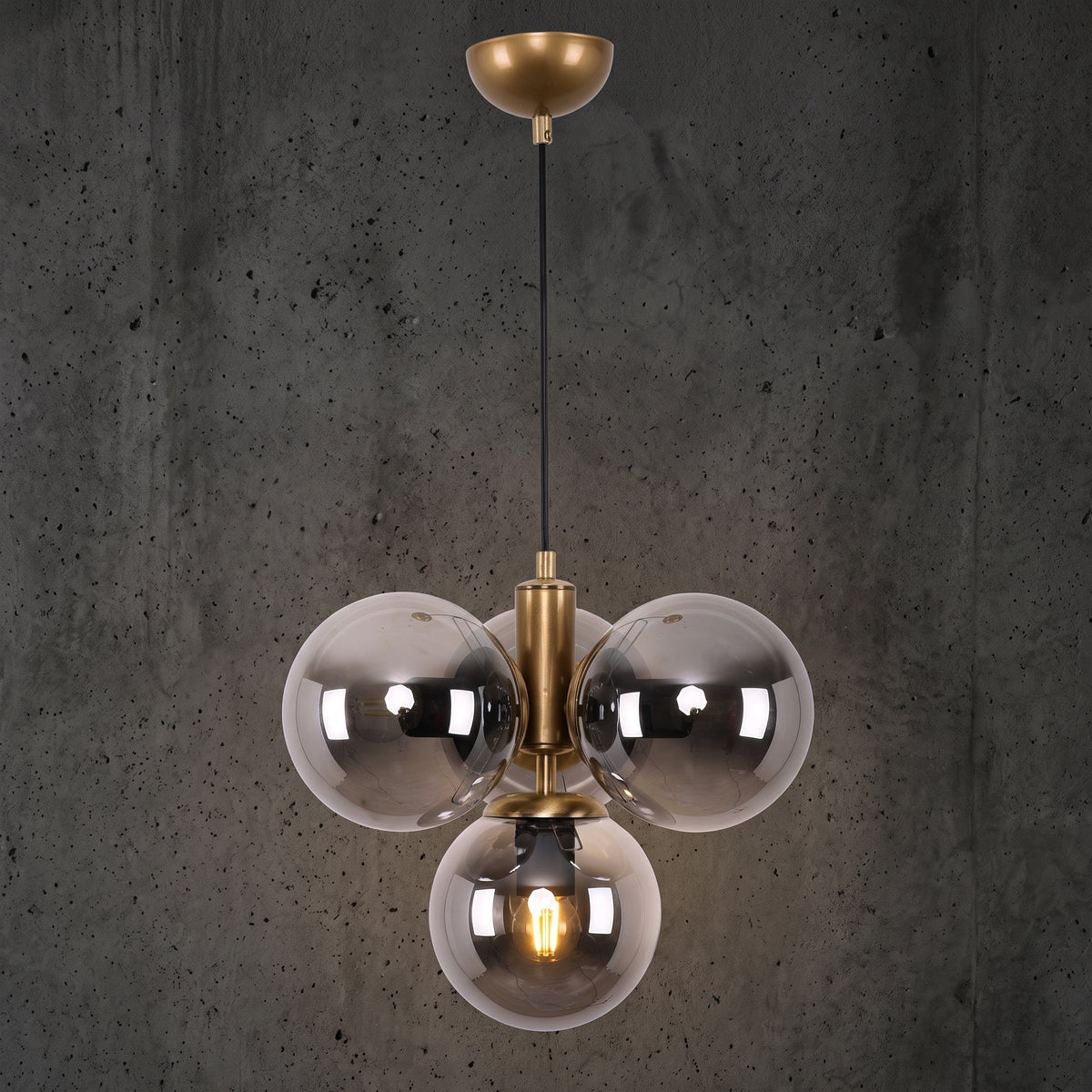 Suspension 4 globes en verre fumé transparent avec structure finition laiton brossé sur fond sombre