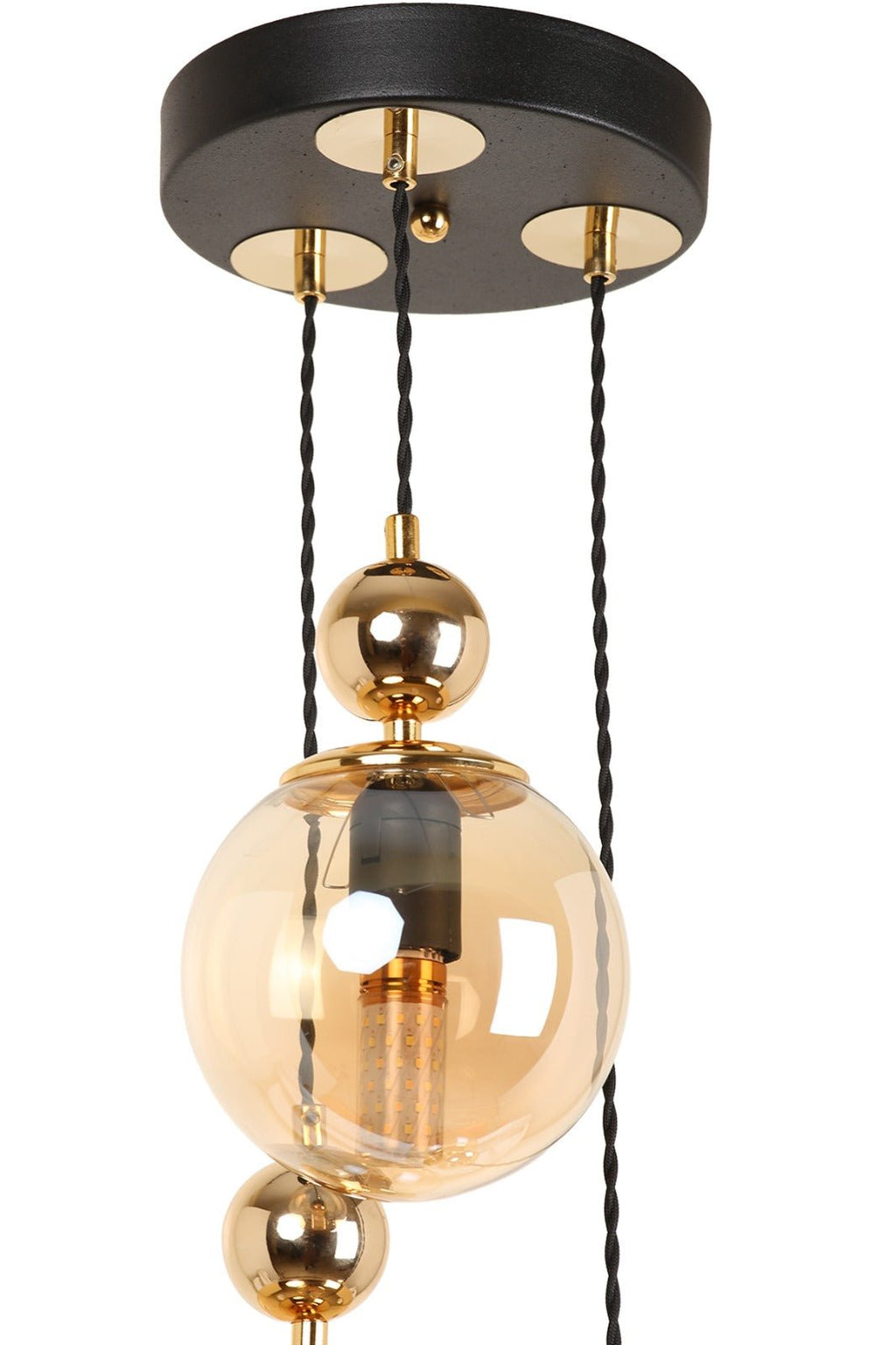 Gros plan sur un globe en verre ambré et les détails dorés de la suspension cascade
