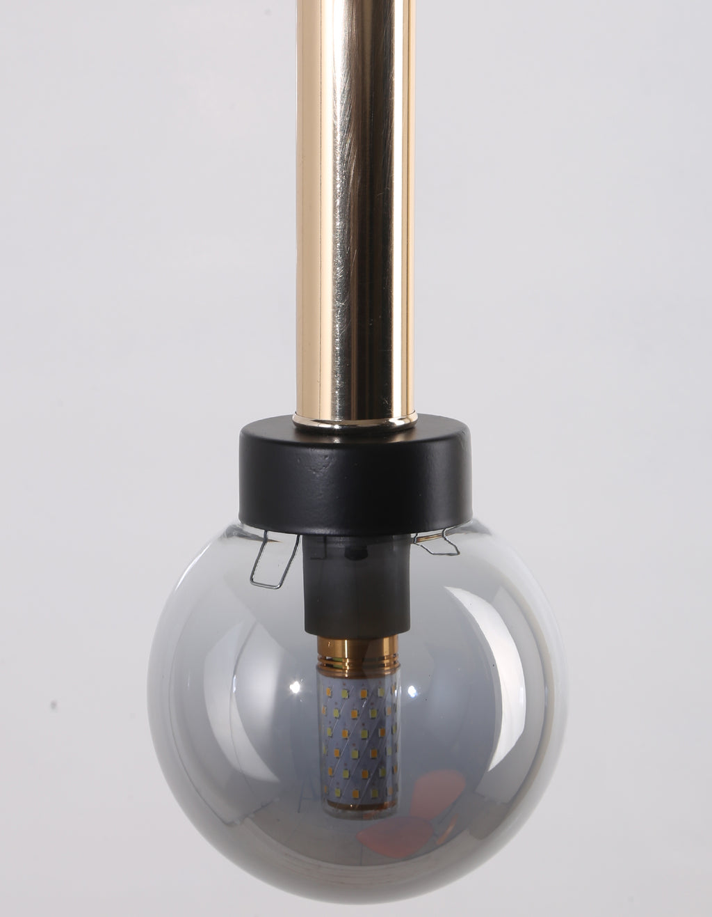 Détail du cylindre doré, de la bague noire et du globe fumé lisse avec ampoule visible
