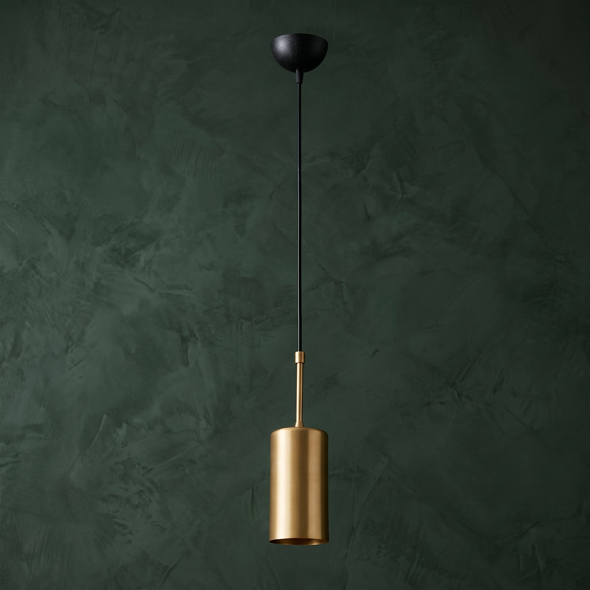 Suspension cylindrique dorée et noire de 9 cm de diamètre sur fond vert foncé