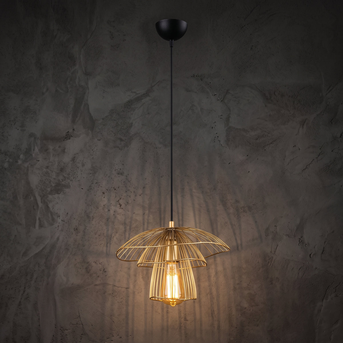 Suspension filaire champignon dorée Ø33 cm allumée sur mur sombre