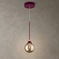 Suspension bordeaux avec détails dorés et globe rond en verre ambré allumé sur fond beige