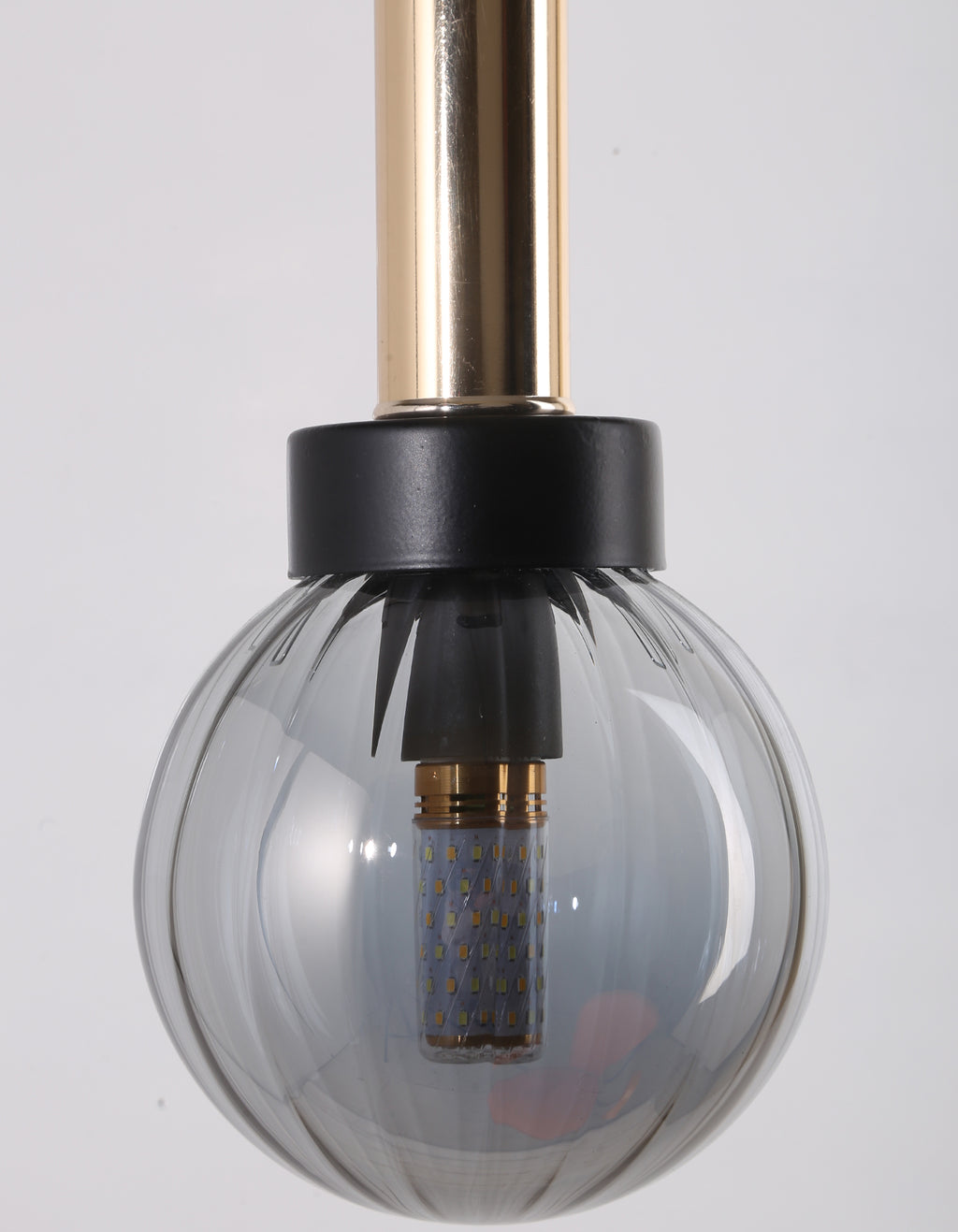 Détail du globe en verre transparent côtelé, de la bague noire et du cylindre métallique doré