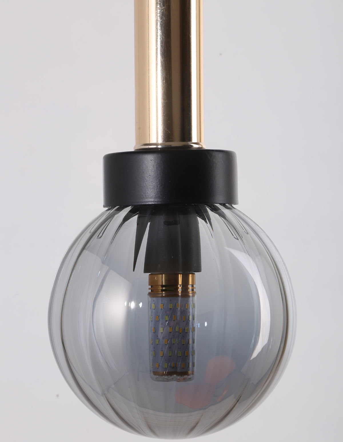 Détail du globe en verre transparent côtelé, de la bague noire et du cylindre métallique doré