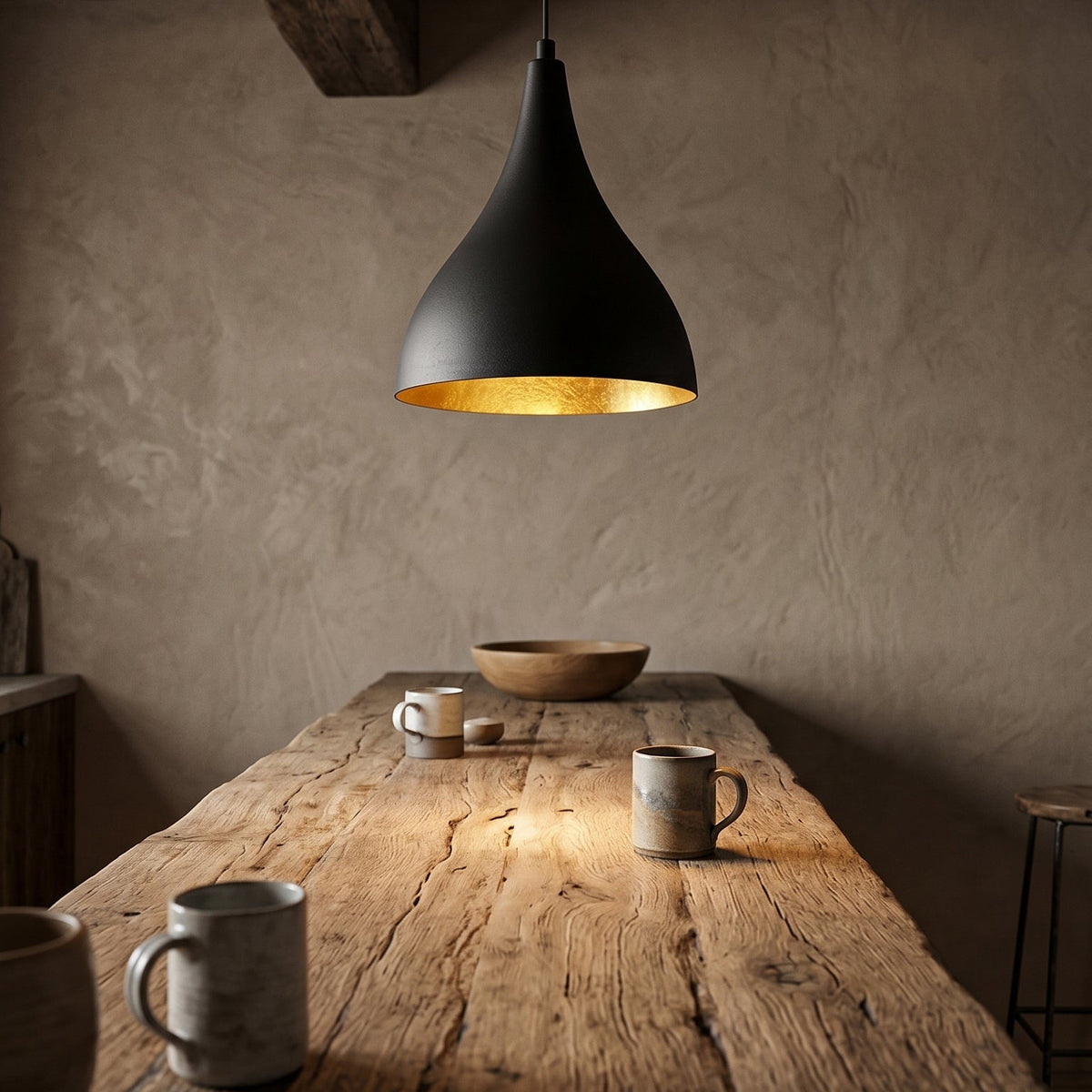 Suspension goutte noir et doré installée au-dessus d’une table en bois