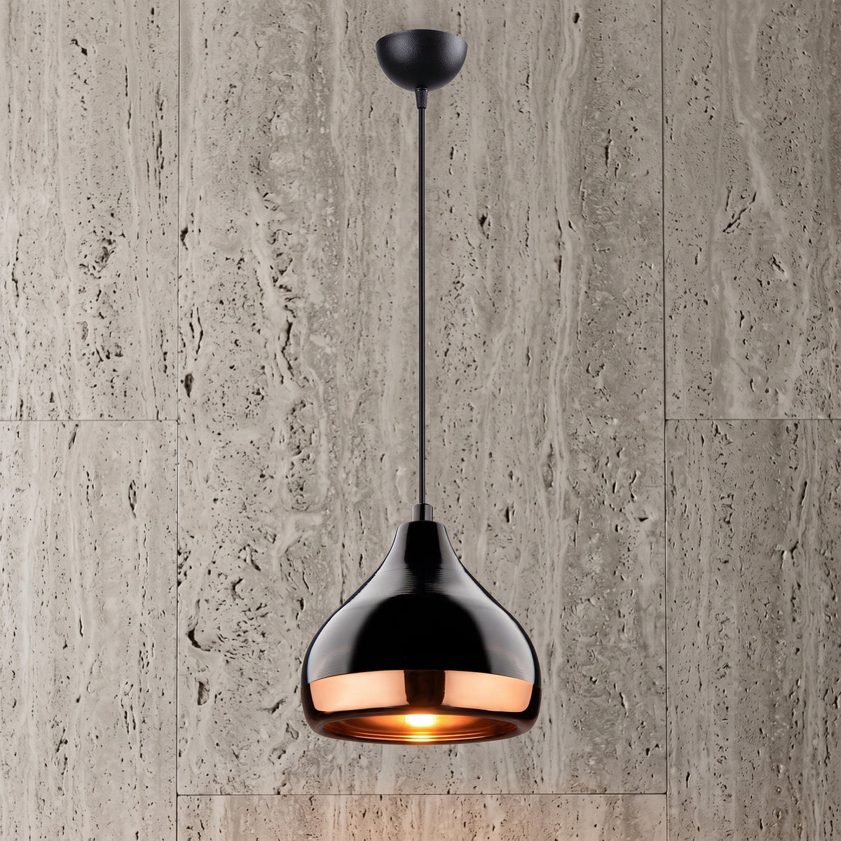 Suspension industrielle noire et rose gold allumée devant un mur en pierre claire